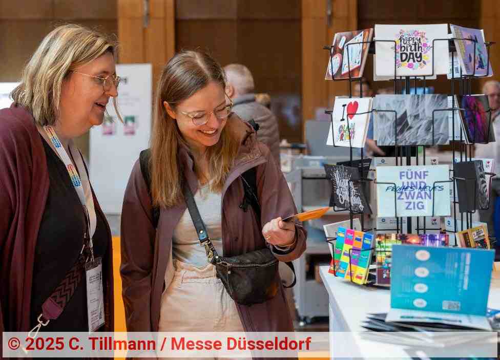 Zwei Frauen, die Postkarten an einem PRINT DIGITAL CONVENTION Messestand betrachten | Foto: C. Tillmann / Messe Düsseldorf Zwei Frauen, die Postkarten an einem PRINT DIGITAL CONVENTION Messestand betrachten | Foto: C. Tillmann / Messe Düsseldorf